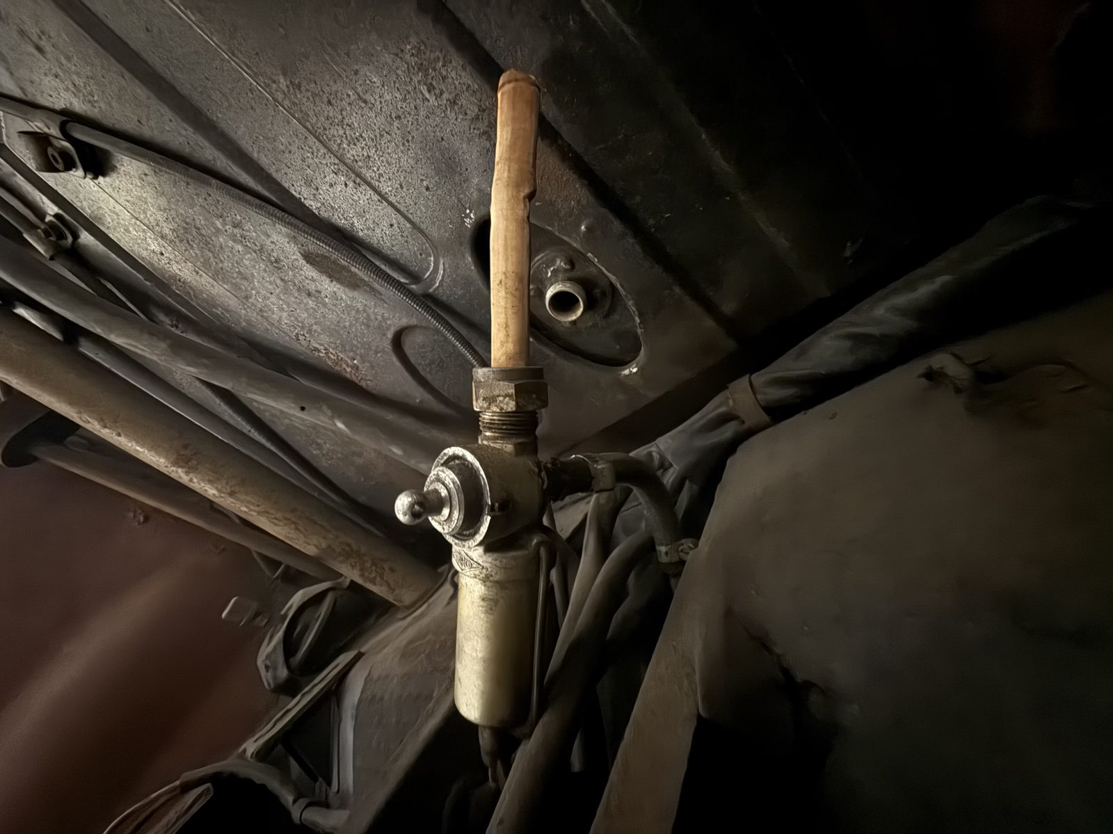 Brass fuel tap and line at the tank outlet, seen from underneath